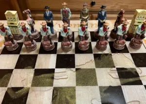 Hand-painted Wild West themed chess set with cowboy and saloon-piece figures set up on a wood board
