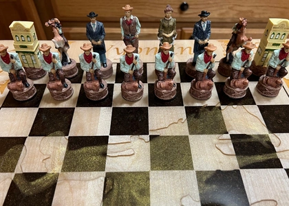 Hand-painted Wild West themed chess set with cowboy and saloon-piece figures set up on a wood board